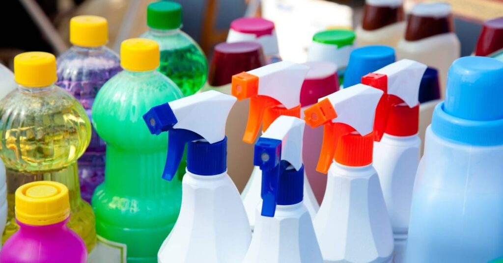 An assorted group of cleaning products. Some bottles are clear with various-colored cleaners while other bottles are solid colors.