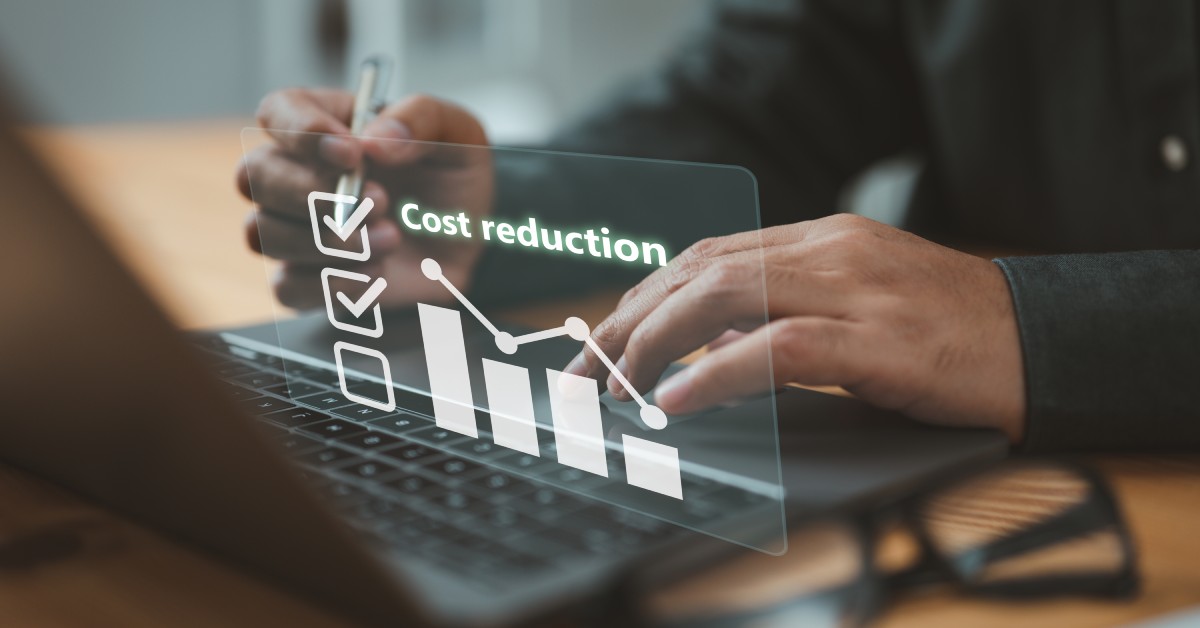 A person typing on a laptop keyboard with a digital screen overlay showing a chart and the phrase "cost reduction."