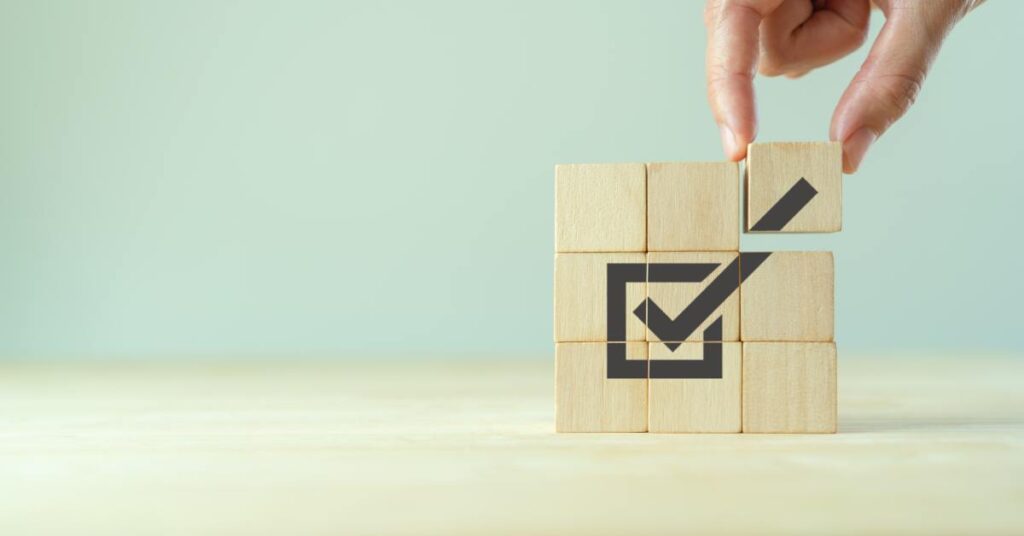 A close-up view shows a hand placing a wooden block on top of others. The blocks are creating a black checkmark.