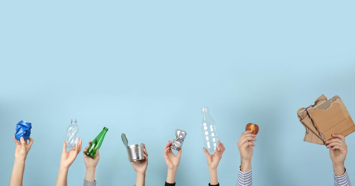Eight hands rise into view, each holding a different type of trash that can be recycled. The background is teal.