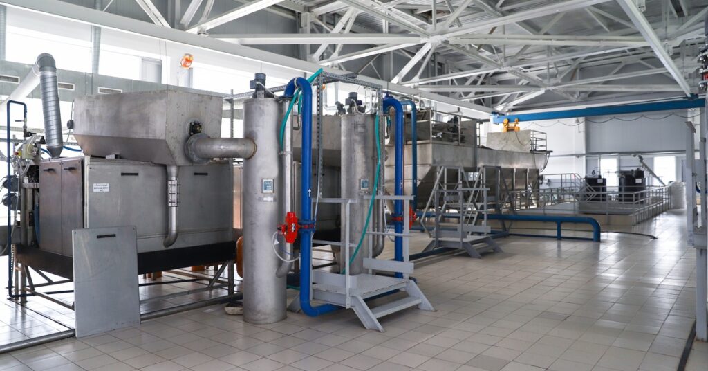 Large industrial containers fill a room and have blue tubes coming on the top of them and down the side.