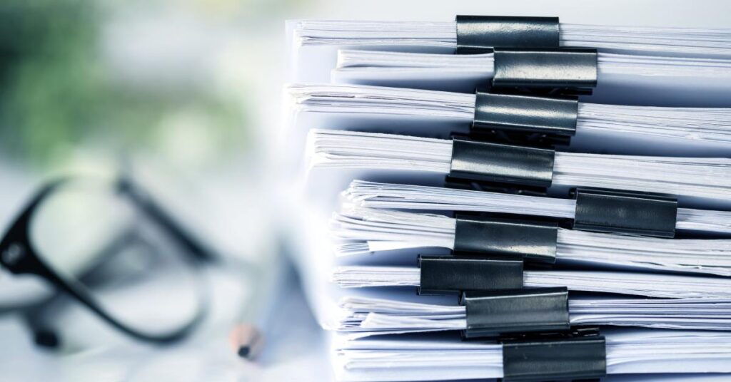 A close-up view shows several bundles of paperwork clipped together with black binder clips stacked on top of each other.