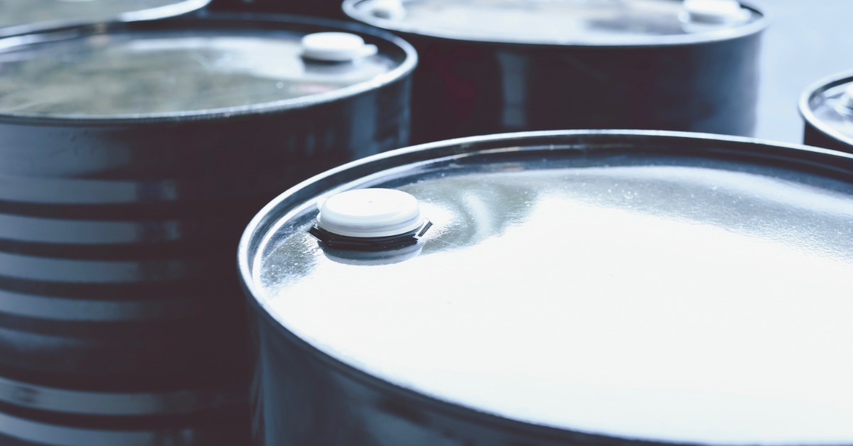 A close-up view shows six black, metal barrels sitting in two lines of three. The barrels have white caps on top.