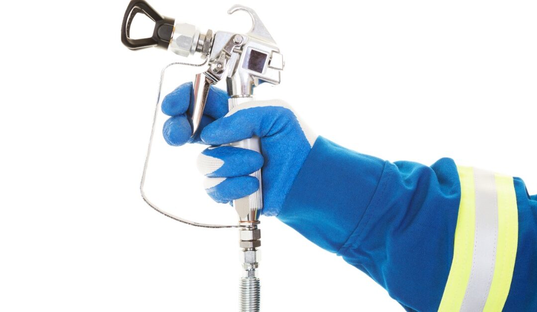 A worker in a blue glove holding an airless spray gun for industrial paint and coating applications tasks on a white background.